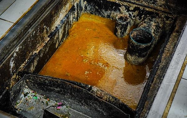 during grease trap cleaning, the trap is emptied, scraped, and cleaned to remove built-up grease and solids